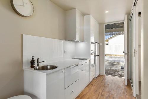 uma cozinha branca com um lavatório e um relógio na parede em Aloha Central Luxury Accommodation em Naracoorte