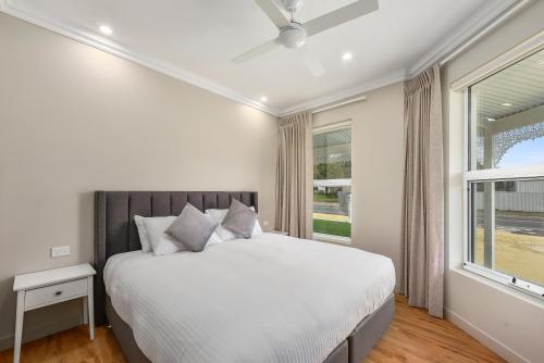 a white bedroom with a large bed and a window at Aloha Central Luxury Accommodation in Naracoorte