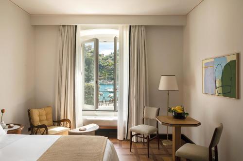 a hotel room with a bed and a table and a window at Splendido Mare, A Belmond Hotel, Portofino in Portofino