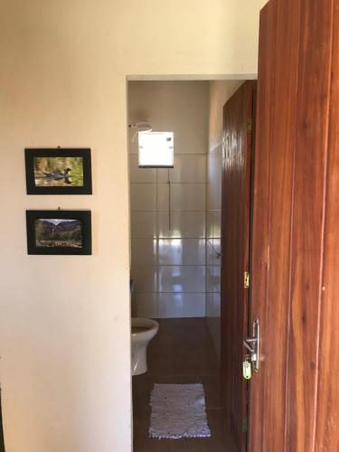 a bathroom with a toilet and a shower and a door at Chalé da Mata in São Roque de Minas