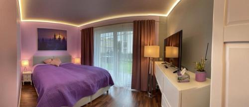 a bedroom with a purple bed and a window at Krejcarek Garden Apartment in Prague