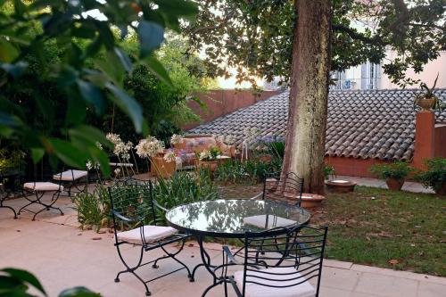 a group of chairs and a glass table in a garden at Siora Vittoria Boutique Hotel in Corfu Town