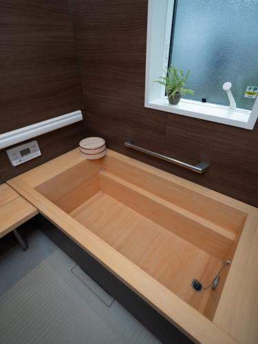 La salle de bains est pourvue d'une baignoire en bois et d'une fenêtre. dans l'établissement Kamakura International House Japanese-style room w Shower Toilette - Vacation STAY 11630, à Kamakura