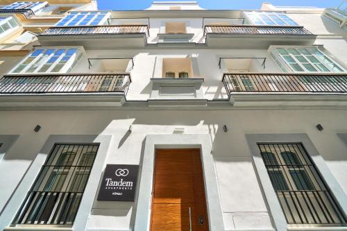 a tall white building with a door and windows at Tandem Pópulo in Cádiz