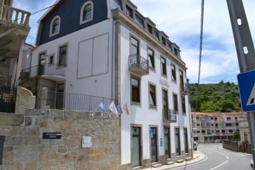 a white building with a black roof on a street at Hotel Comércio in Resende