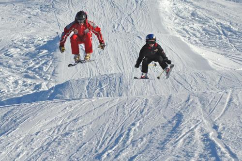 two people are skiing down a snow covered slope at Chalet Balthazar in Villars-sur-Ollon