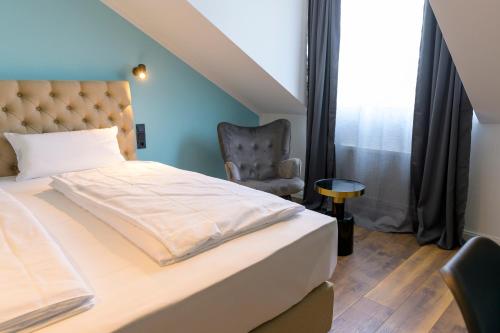 a bedroom with a bed and a chair at Nikii City Hotel in Leverkusen