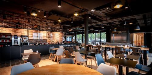 un restaurant avec des tables et des chaises ainsi qu'un bar dans l'établissement ibis Styles Valenciennes Petite Foret, à Petite-Forêt