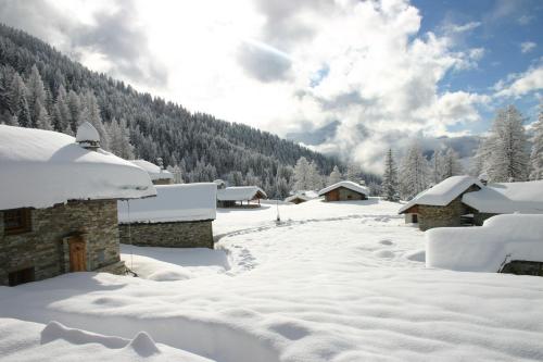 a snow covered yard with houses and trees at Baita La Jolie Bergere in La Salle
