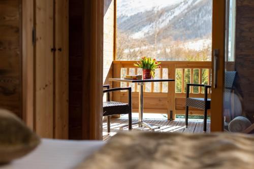 a table and chairs on a balcony with a view at Hôtel Ski Lodge - Chambres & Appartements - Village Montana in Val dʼIsère
