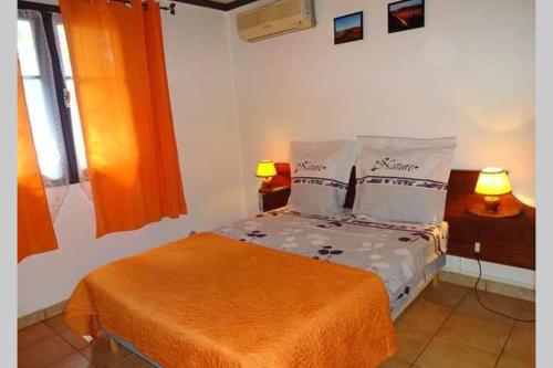 ein Schlafzimmer mit einem Bett mit einer orangefarbenen Decke und Kissen in der Unterkunft Le Ravenal in Saint-Louis