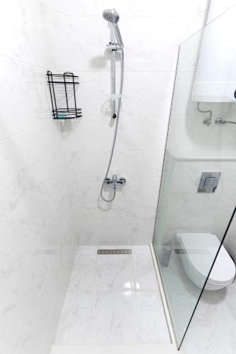 a white bathroom with a shower and a toilet at boulevard apartments in Batumi