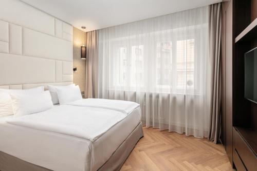 sypialnia z 2 białymi łóżkami i oknem w obiekcie Rybna Apartments Old Town Prague w Pradze