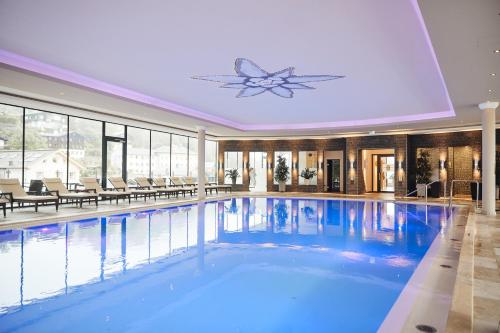 a large swimming pool with blue water in a building at Hotel EDELWEISS Berchtesgaden Superior in Berchtesgaden
