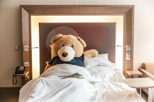a teddy bear sitting on top of a bed at Novotel Toulouse Centre Wilson in Toulouse