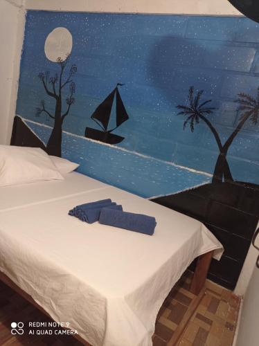 a bedroom with a bed with a painting on the wall at HOSTAL BELLEZA TROPICAL in Moñitos