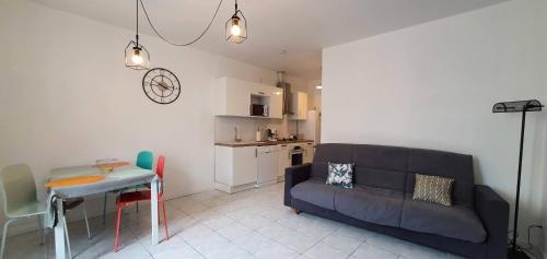 un salon avec un canapé et une table et une cuisine dans l'établissement Chez Mamita : appartement dans quartier calme., à Carcassonne