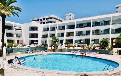 a swimming pool in front of a large building at Optimist Playa de Las Américas in Playa de las Americas