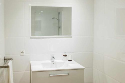 bagno bianco con lavandino e specchio di Playa de Levante Jazmines 16 a Benidorm