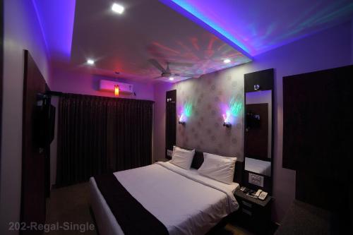 a bedroom with a bed with a purple lighting at Vijaya Residency - Porur in Chennai