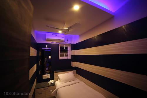 a small room with a bed and a purple light at Vijaya Residency - Porur in Chennai
