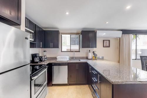 a kitchen with black cabinets and a white refrigerator at The Cove 9 at Playa Ocotal in Coco