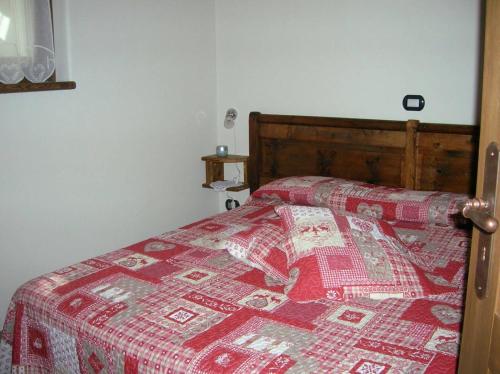 1 dormitorio con 1 cama con edredón rojo en La Petite Maison, en Arvier