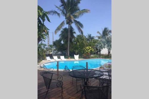 eine Terrasse mit einem Tisch und Stühlen neben einem Pool in der Unterkunft Le Pavillon in Saint-Louis