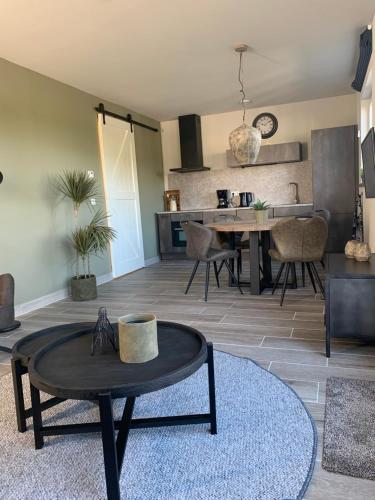 a living room with a table and a kitchen at Dijkhofje, dichtbij strand, zee en meer. in Vrouwenpolder