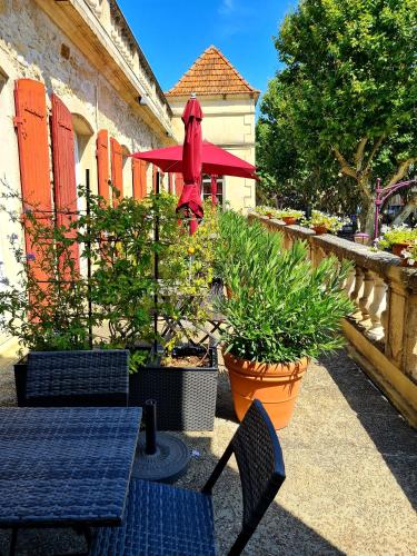 a patio with tables and chairs and a red umbrella at Hotel Des Artistes in Tarascon