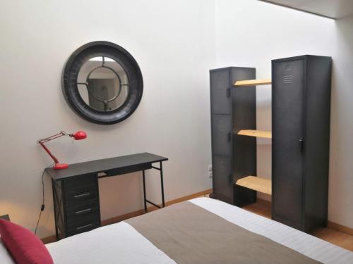1 dormitorio con cama, escritorio y espejo en Gîte La filature, en Saint-Quentin