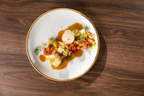 a plate of food with vegetables and gravy on a table at Gostišče Iršič in Slovenska Bistrica