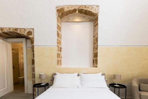 a bedroom with a large white bed with two tables at Palazzo Balsamo in Gallipoli