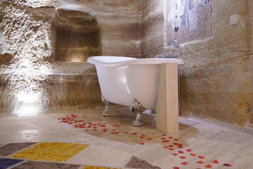 a bathroom with a bath tub with red flowers on the floor at Göreme Cave Lodge in Goreme