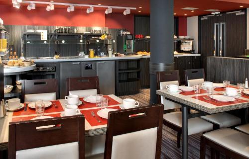 a restaurant with a table and chairs and a kitchen at Hôtel Alba in Lourdes