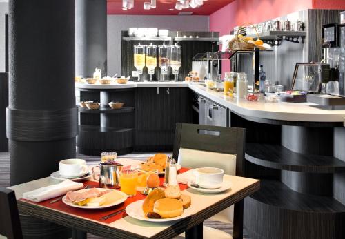 a restaurant with a table with food on it at Hôtel Alba in Lourdes