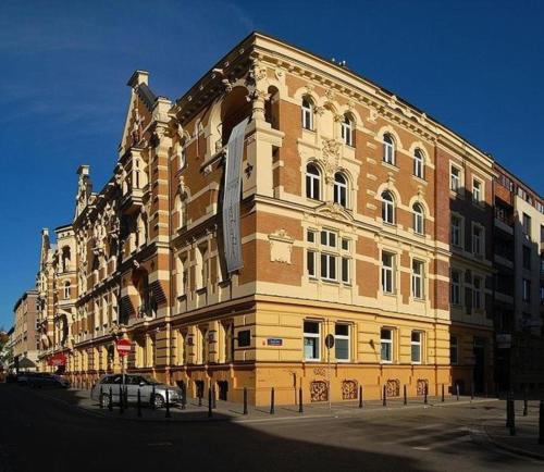ワルシャワにあるMoon Hostel Warszawaの大きなレンガ造りの建物で、車が正面に駐車しています。