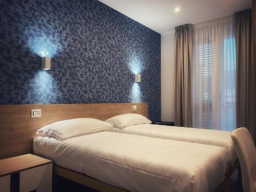 two beds in a hotel room with blue wallpaper at Lumarooms B&B in Reggio Calabria