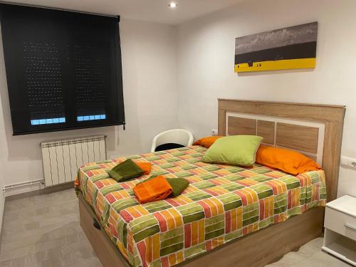 a bedroom with a bed with orange and green pillows at Apartament Margarit in Girona