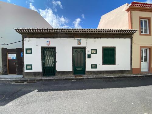 a white building with green doors on a street at Alojamento dos Oleiros in Vila Franca do Campo