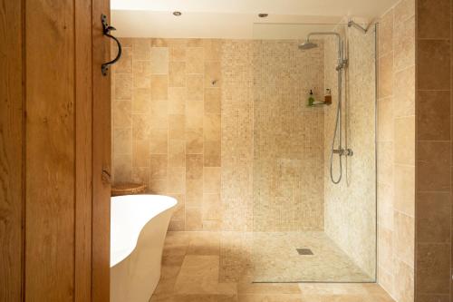a bathroom with a shower with a tub and a sink at Woodpecker Loft at Millfields Farm Cottages in Ashbourne
