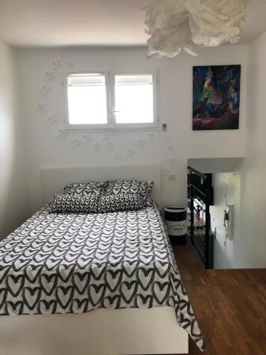 een slaapkamer met een bed met een zwart-wit dekbed bij L’échappée Bulles in Épernay
