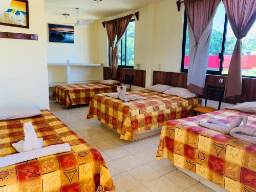a hotel room with three beds and windows at Hotel Sociedad y Maristas in Tecolutla