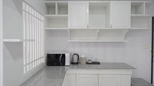 a kitchen with white cabinets and a microwave at RoomQuest Nichada ISB International in Ban Bang Talat