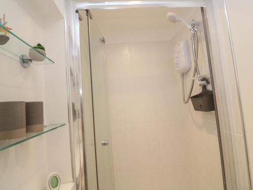 a shower with a glass door in a bathroom at Primrose Cottage in Hayle