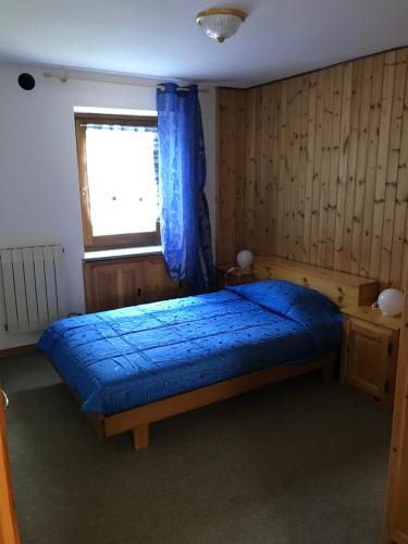 a bedroom with a blue bed and a window at Appartamenti Il Castello in Saint-Pierre