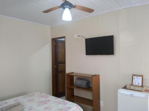 a bedroom with a ceiling fan and a television on the wall at Pousada Marimbá in Trindade