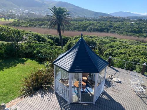 a gazebo on top of a wooden deck with a palm tree at Kennedys Beach Villa in Hermanus