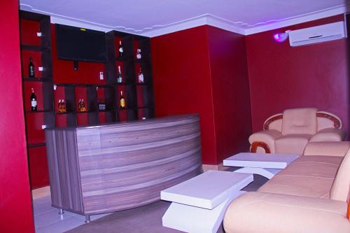 um quarto vermelho com um bar com televisão e cadeiras em Bethel Resort & Hotels em Gulu