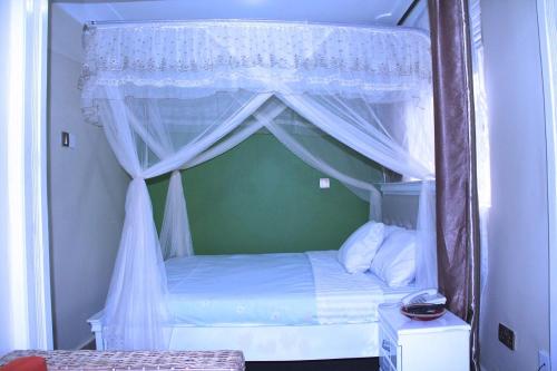 a bedroom with a canopy bed with white curtains at Bethel Resort & Hotels in Gulu